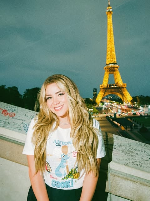 Carolina sonriendo frente a la Torre Eiffel iluminada